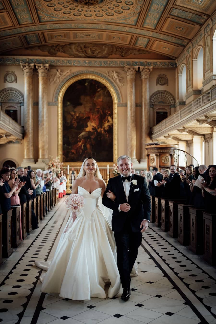 Image of a bride and groom walking down the aisle of an ornate church.