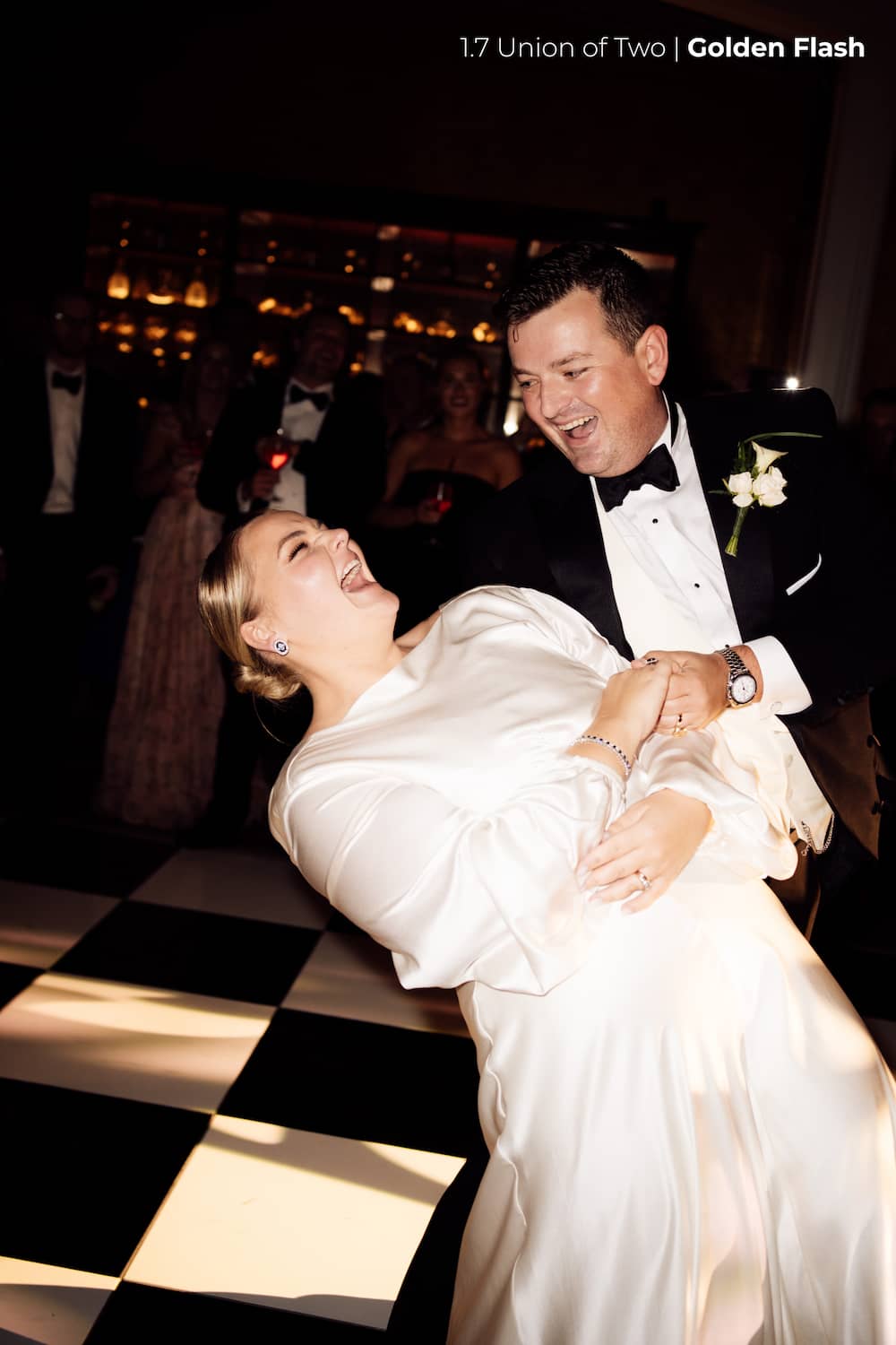 A bride and groom are dancing on a checkerboard dance floor as wedding guests in tuxedos and dress can be faintly seen in the background, edited with the Union of Two 2.0 Preset Pack.